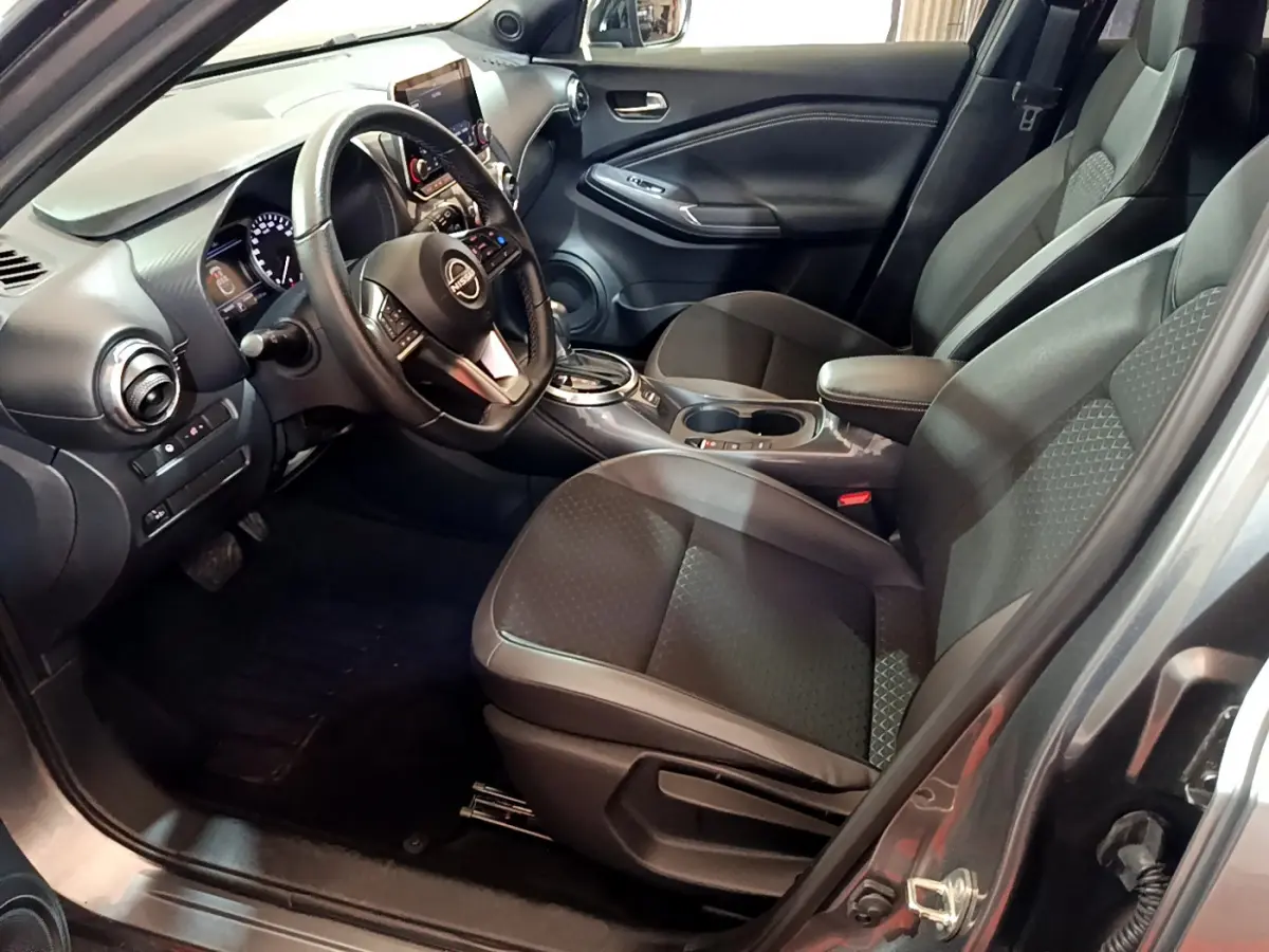 Intérieur avant droit du Nissan Juke Hybrid 143 Business+ 2023 avec sièges noirs et tableau de bord moderne.