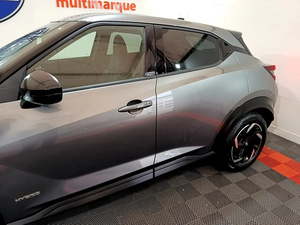 Profil côté gauche du Nissan Juke Hybrid 143 Business+ gris foncé, mettant en valeur les jantes noires et le logo Hybrid.