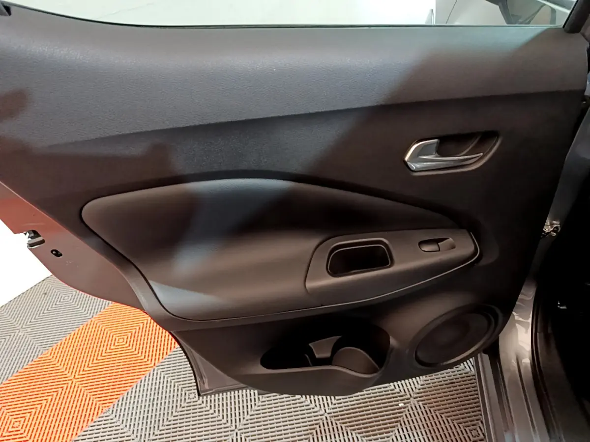 Porte intérieure côté gauche du Nissan Juke Hybrid 143 Business+ 2023 en gris foncé avec poignée et commandes de vitre.