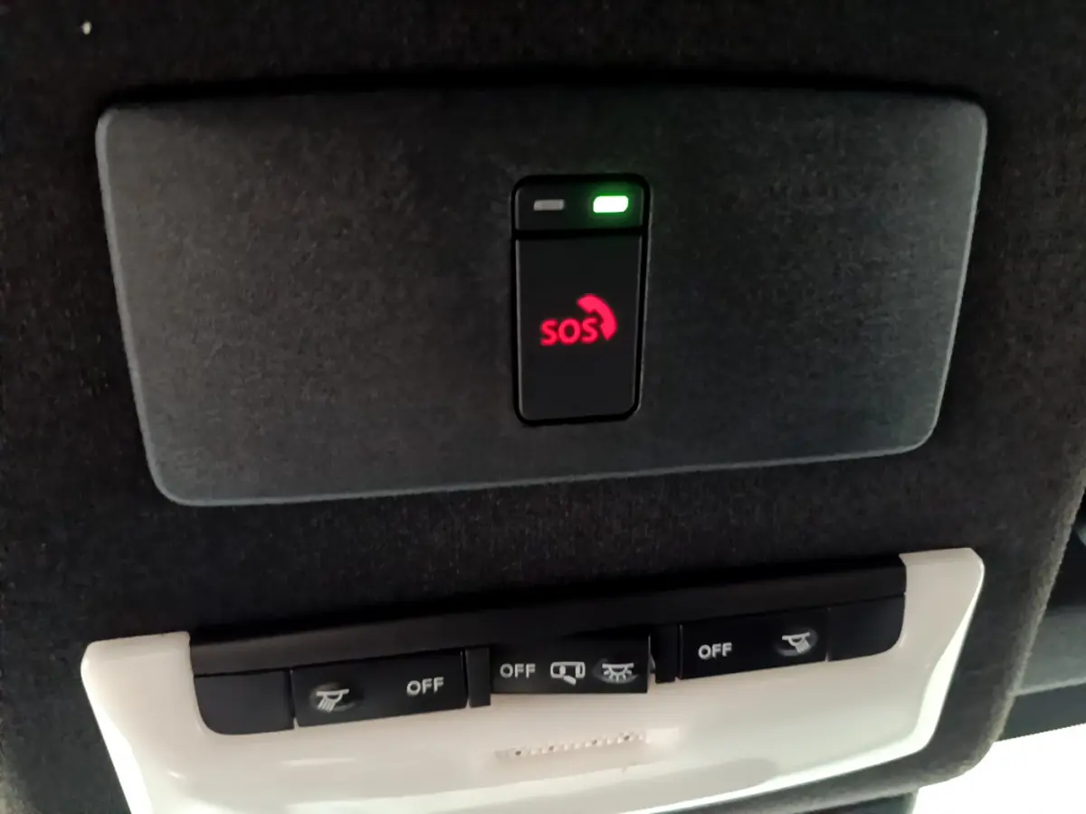 Détail du plafonnier noir avec bouton SOS rouge et commandes d'éclairage dans un Nissan Juke Hybrid gris foncé 2023.