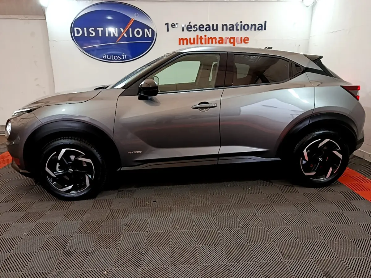 Profil droit du Nissan Juke Hybrid 143 Business+ gris foncé, avec jantes noires à motifs argentés.