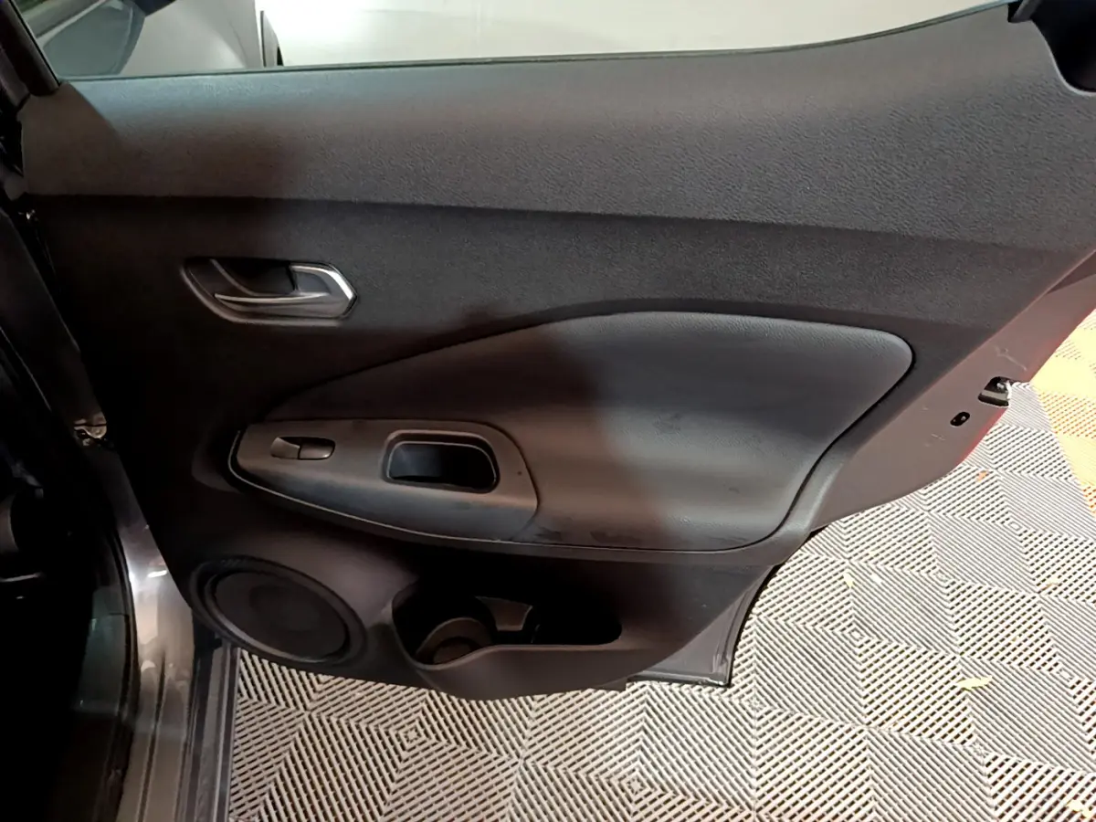 Vue rapprochée de la porte arrière droite gris foncé du Nissan Juke Hybrid 143 Business+ avec poignée et haut-parleur intégrés.
