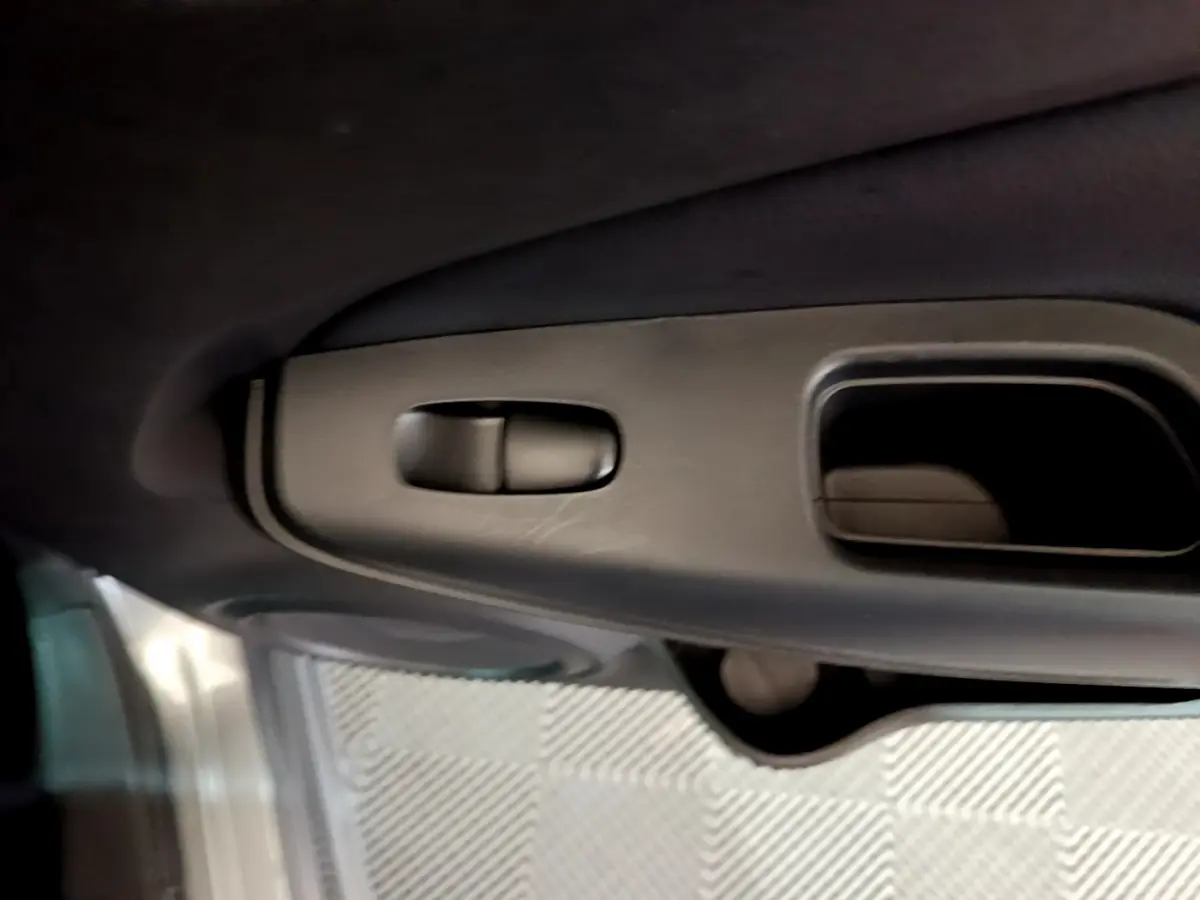 Détail de la poignée intérieure de porte côté gauche du Nissan Juke Hybrid 143 Business+ gris foncé 2023.