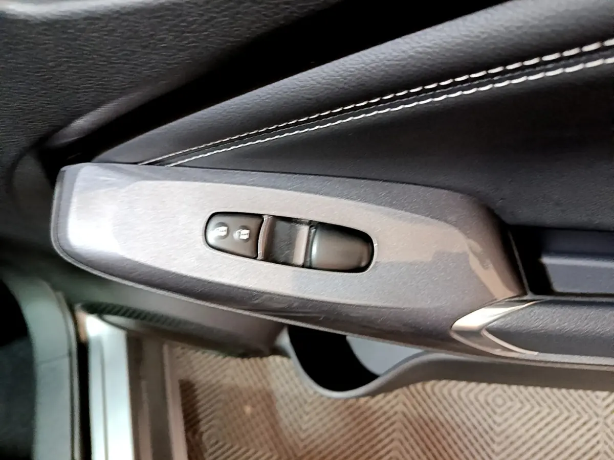 Gros plan sur la commande de verrouillage des portes côté conducteur dans l'habitacle noir du Nissan Juke Hybrid 2023.