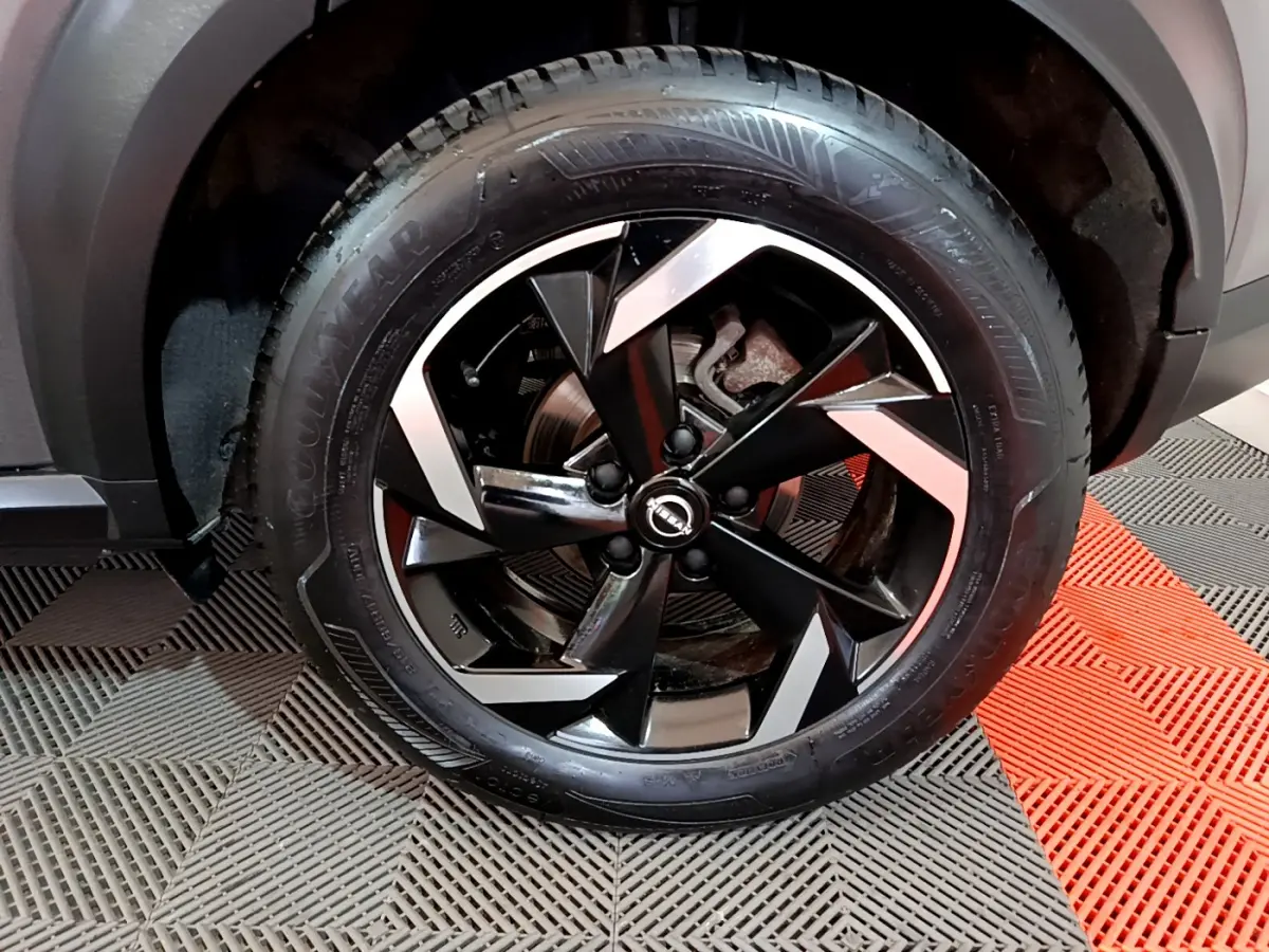 Gros plan sur la roue avant droite du Nissan Juke Hybrid 143 Business+ gris foncé avec jante noire et argentée.