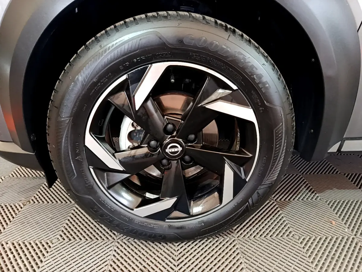 Gros plan sur la roue avant droite du Nissan Juke Hybrid 143 Business+ gris foncé avec jante noire et argentée design moderne.