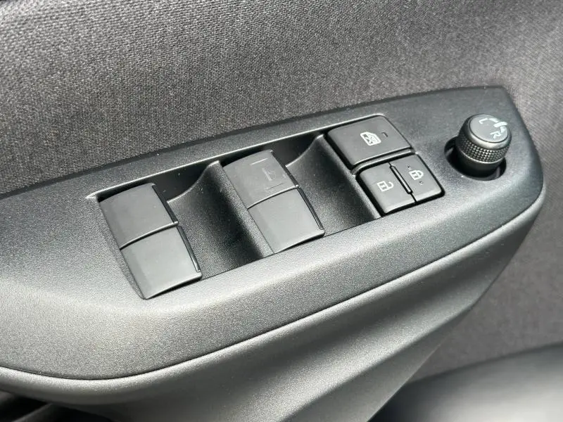 Gros plan sur les commandes de lève-vitres et rétroviseurs côté conducteur d'une Toyota Yaris blanche 2025.