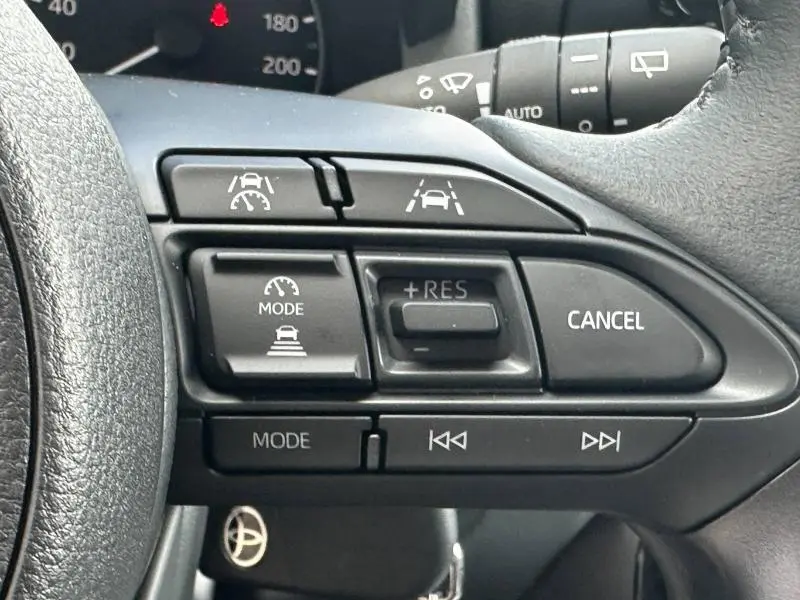 Gros plan sur les commandes au volant de la Toyota Yaris 116h Dynamic 2025, montrant les boutons de régulateur et d'aide à la conduite.