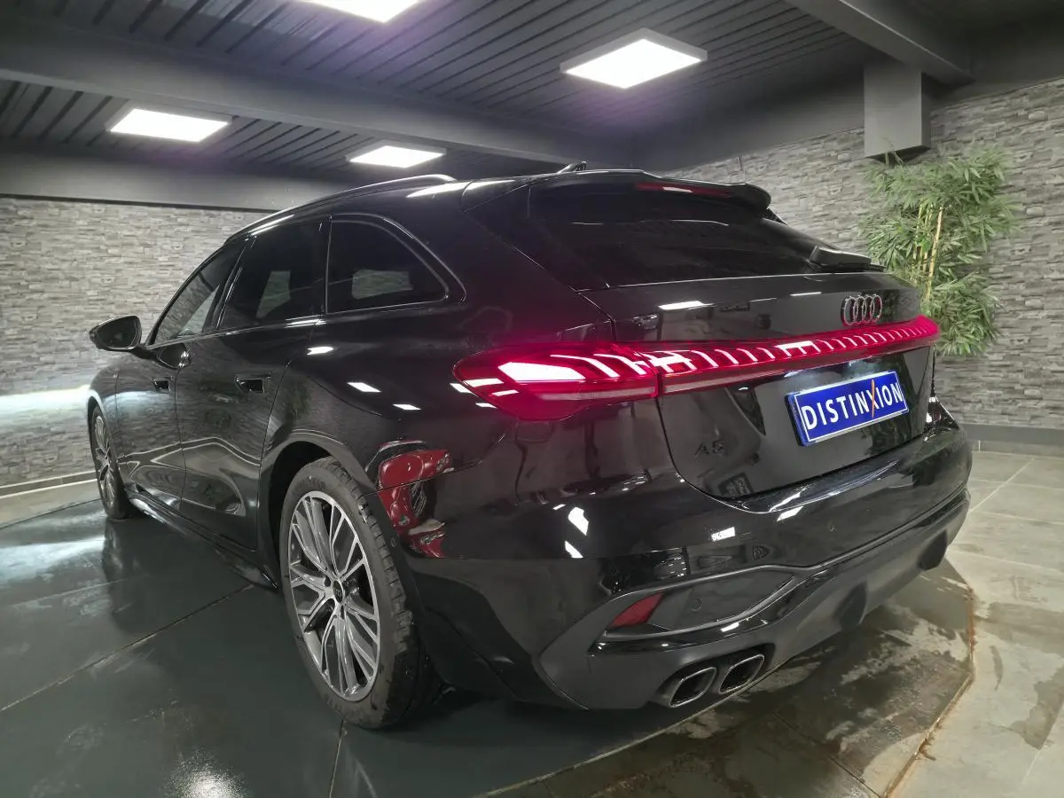 Audi A5 Avant noire vue en 3/4 arrière droit, avec feux arrière LED allumés et jantes 19 pouces style V.