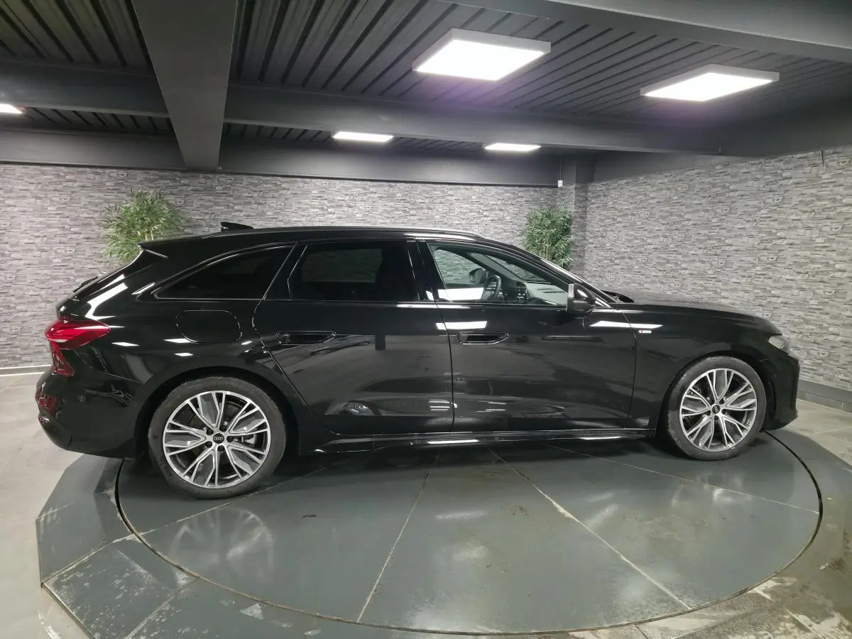 Audi A5 Avant noir vue de profil côté gauche, avec jantes 19 pouces et finitions S line visibles en intérieur urbain.