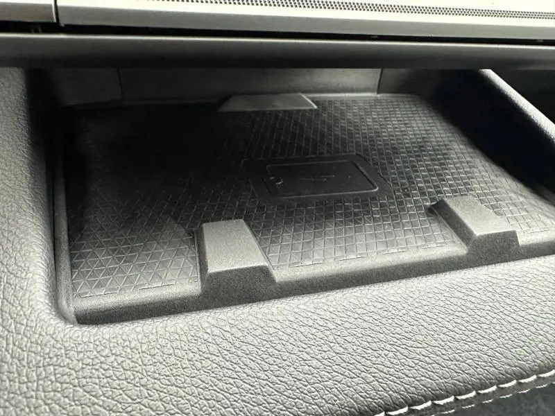 Gros plan sur le plateau de recharge sans fil noir dans l'habitacle du Renault Scénic E-Tech rouge.