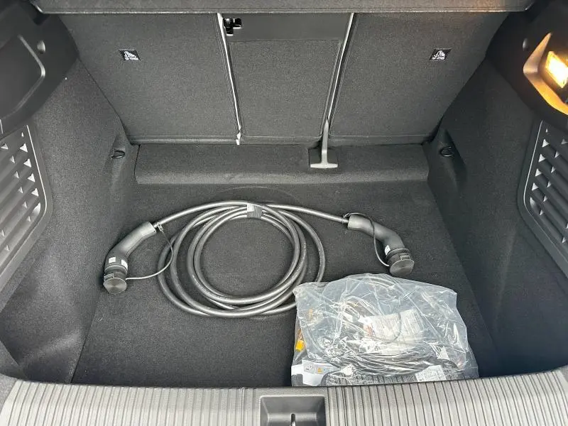 Vue intérieure du coffre noir du Renault Scénic E-Tech électrique 2025 avec câble de recharge visible.