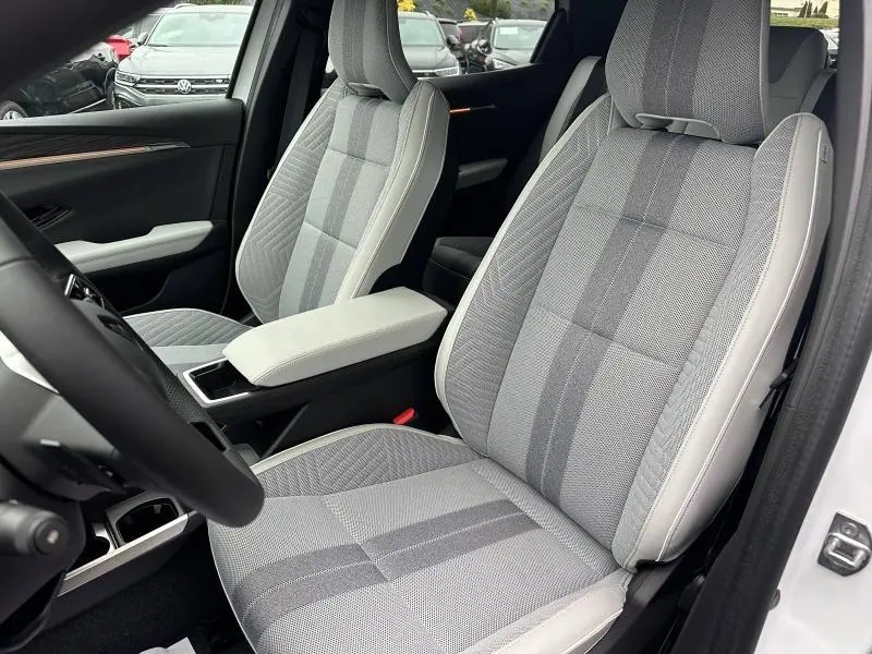 Vue intérieure rapprochée des sièges avant gris clair à motifs du Renault Scenic E-Tech Electric 2025 avec accoudoir central.