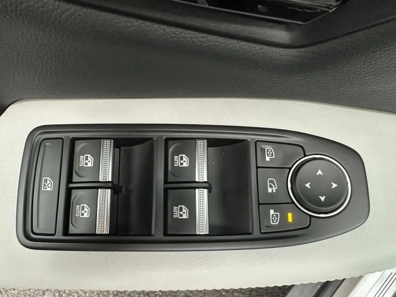 Vue rapprochée des commandes de lève-vitres et rétroviseurs sur la porte côté gauche d’un Renault Scénic rouge 2025.