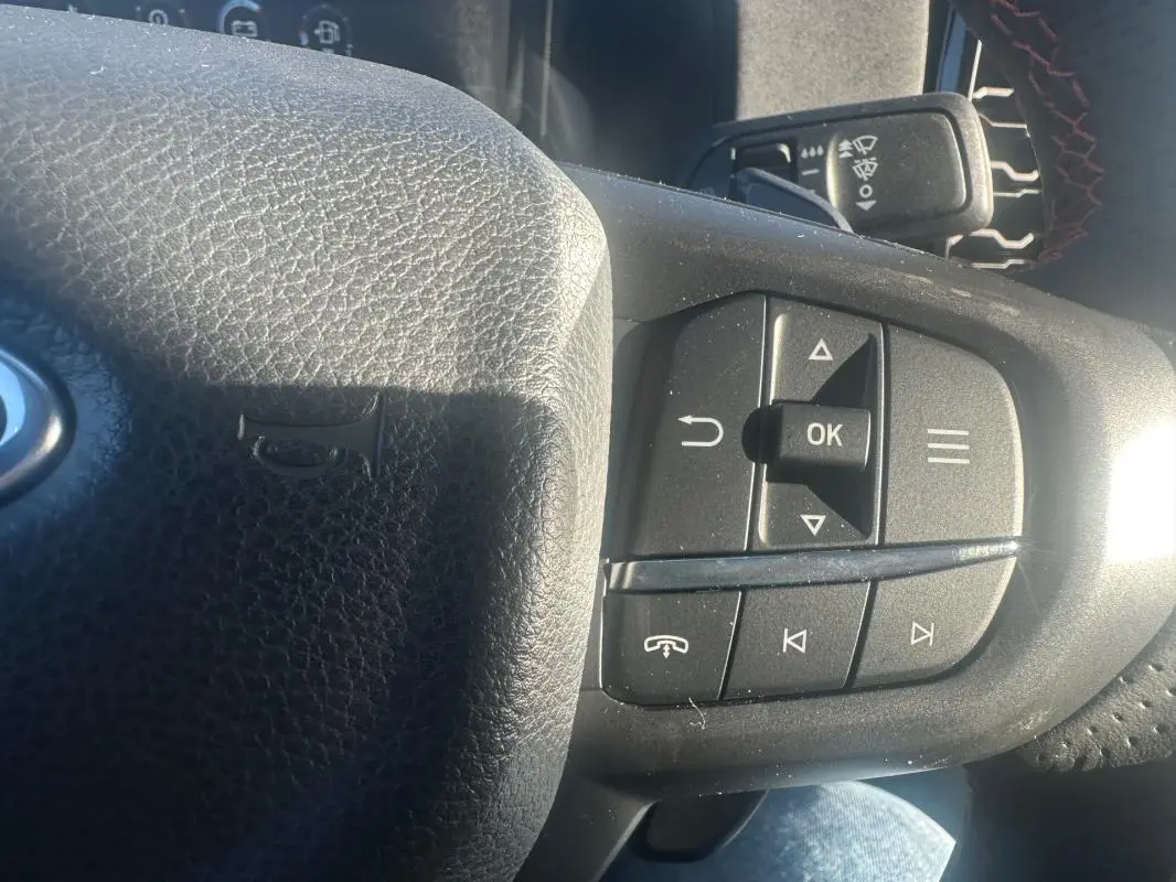 Gros plan sur les commandes multifonctions à droite du volant noir du Ford Ranger blanc 2025.