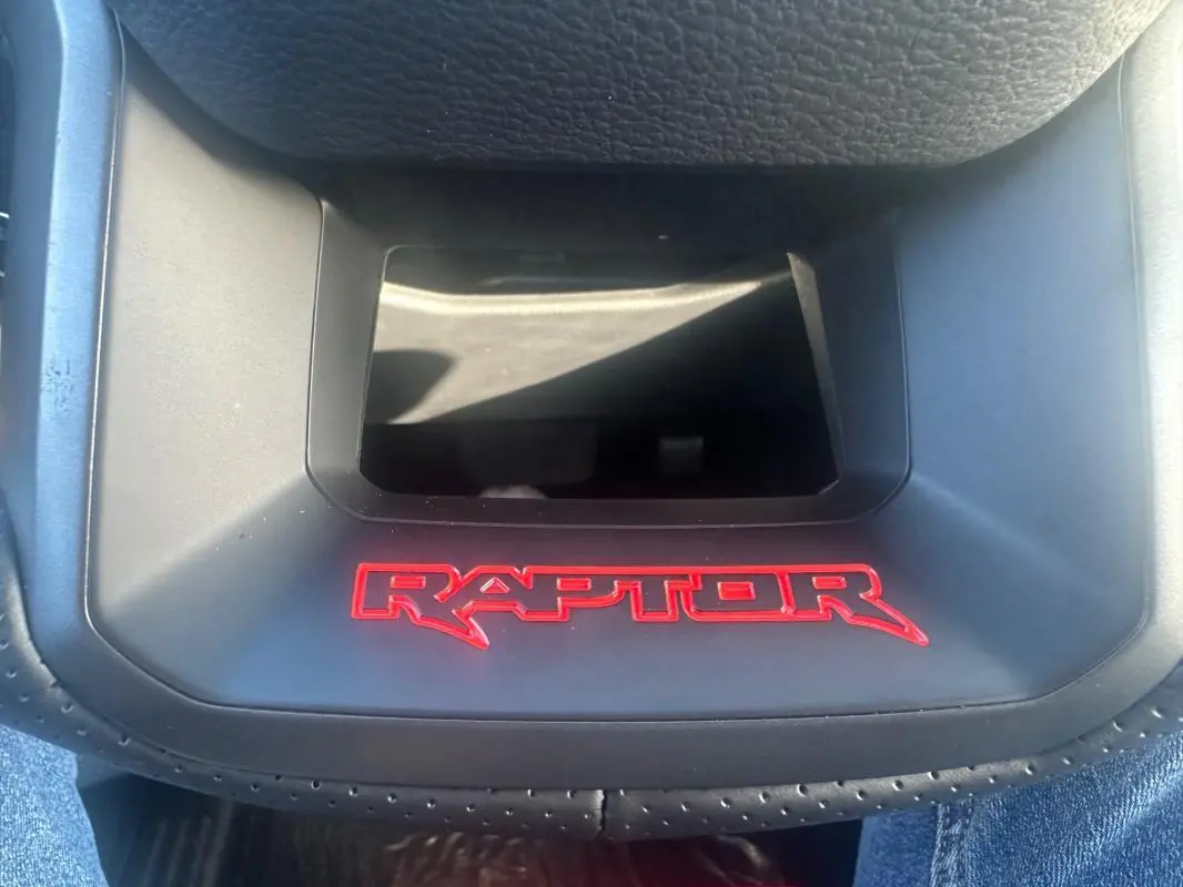 Gros plan sur le logo rouge RAPTOR sur la console centrale noire du Ford Ranger Double Cabine blanc.