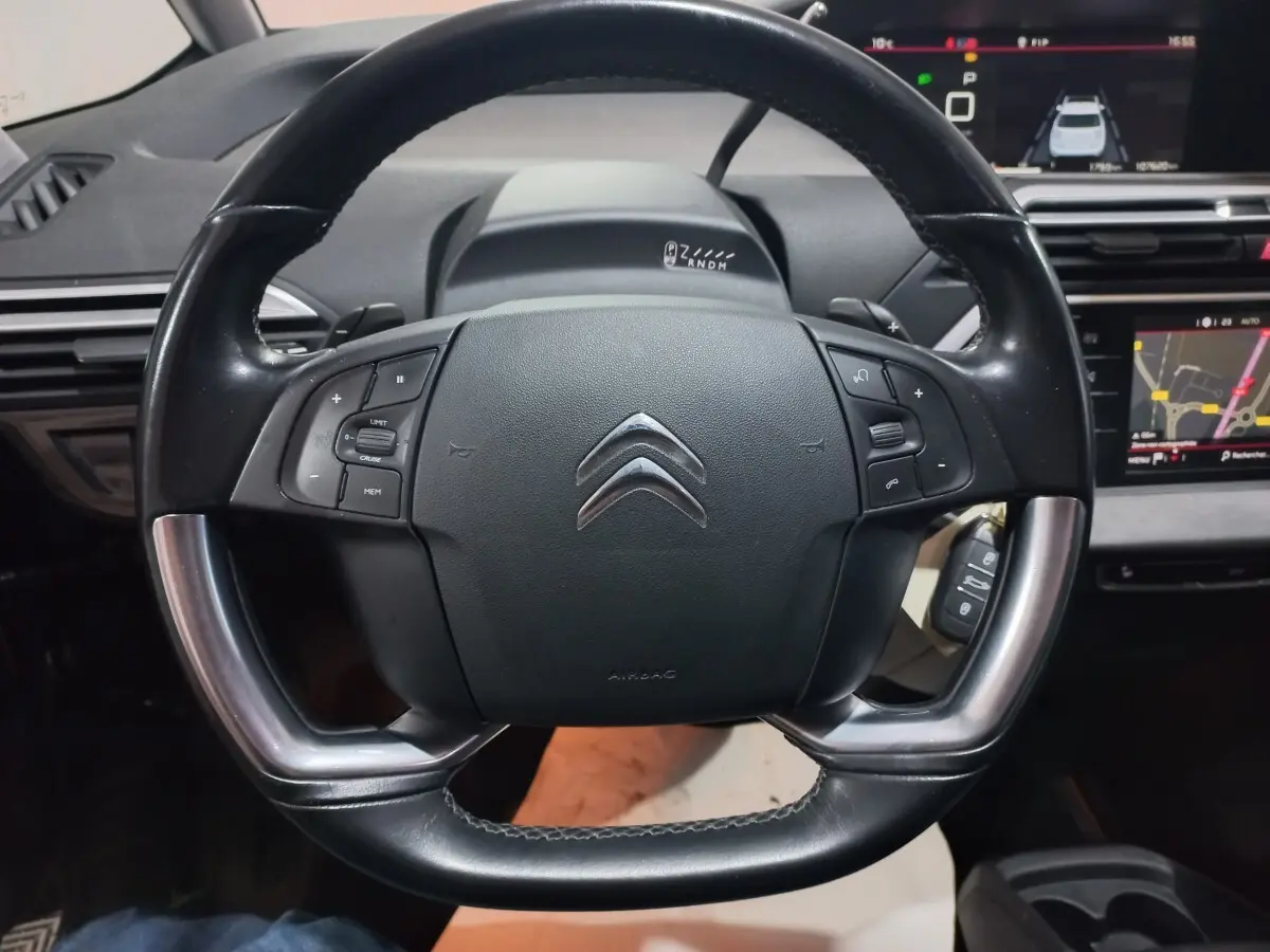 Vue rapprochée du volant cuir noir et alu du Citroën Grand C4 Spacetourer avec tableau de bord et écrans tactiles visibles.