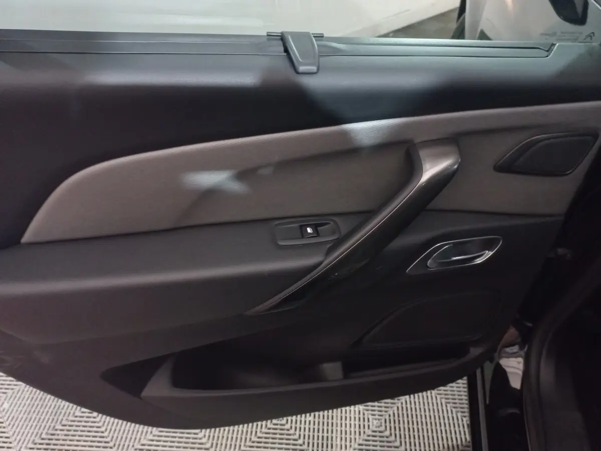 Vue intérieure côté gauche de la porte arrière noire du Citroën Grand C4 Spacetourer avec poignée argentée et bouton de verrouillage.