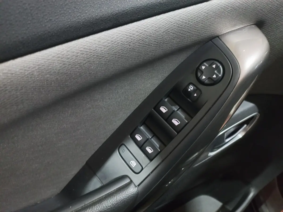 Gros plan sur la commande des vitres électriques côté conducteur d’un Citroën Grand C4 Spacetourer noir, intérieur tissu gris.