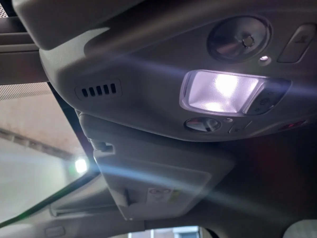 Vue intérieure en plongée sur le plafonnier avec lumière allumée et pare-soleil baissé du Citroën Grand C4 Spacetourer noir.