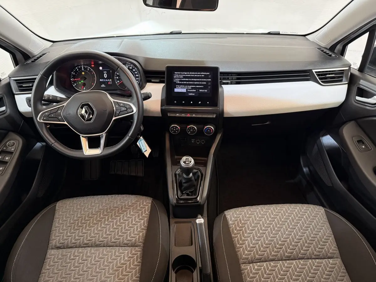 Vue intérieure avant de la Renault Clio Business TCe 100 GPL 2022, volant cuir, écran tactile central et sièges tissu gris.