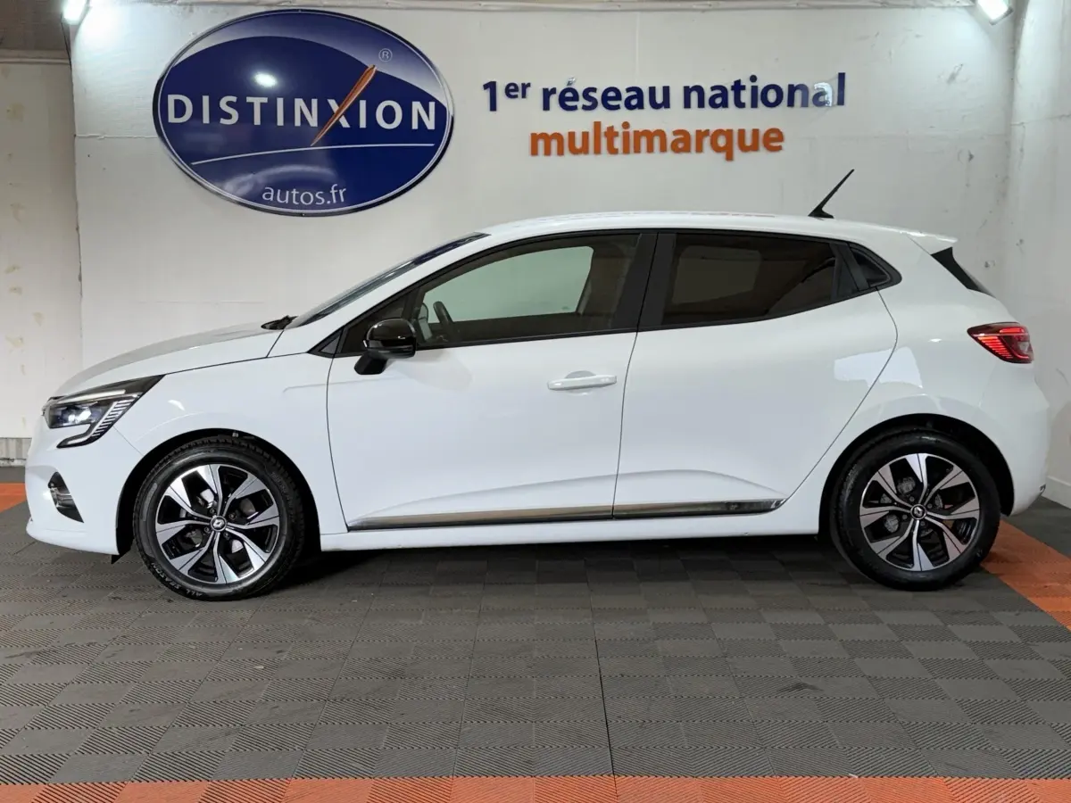 Profil droit d'une Renault Clio Business blanche, avec jantes alliage bicolores et rétroviseurs noirs.