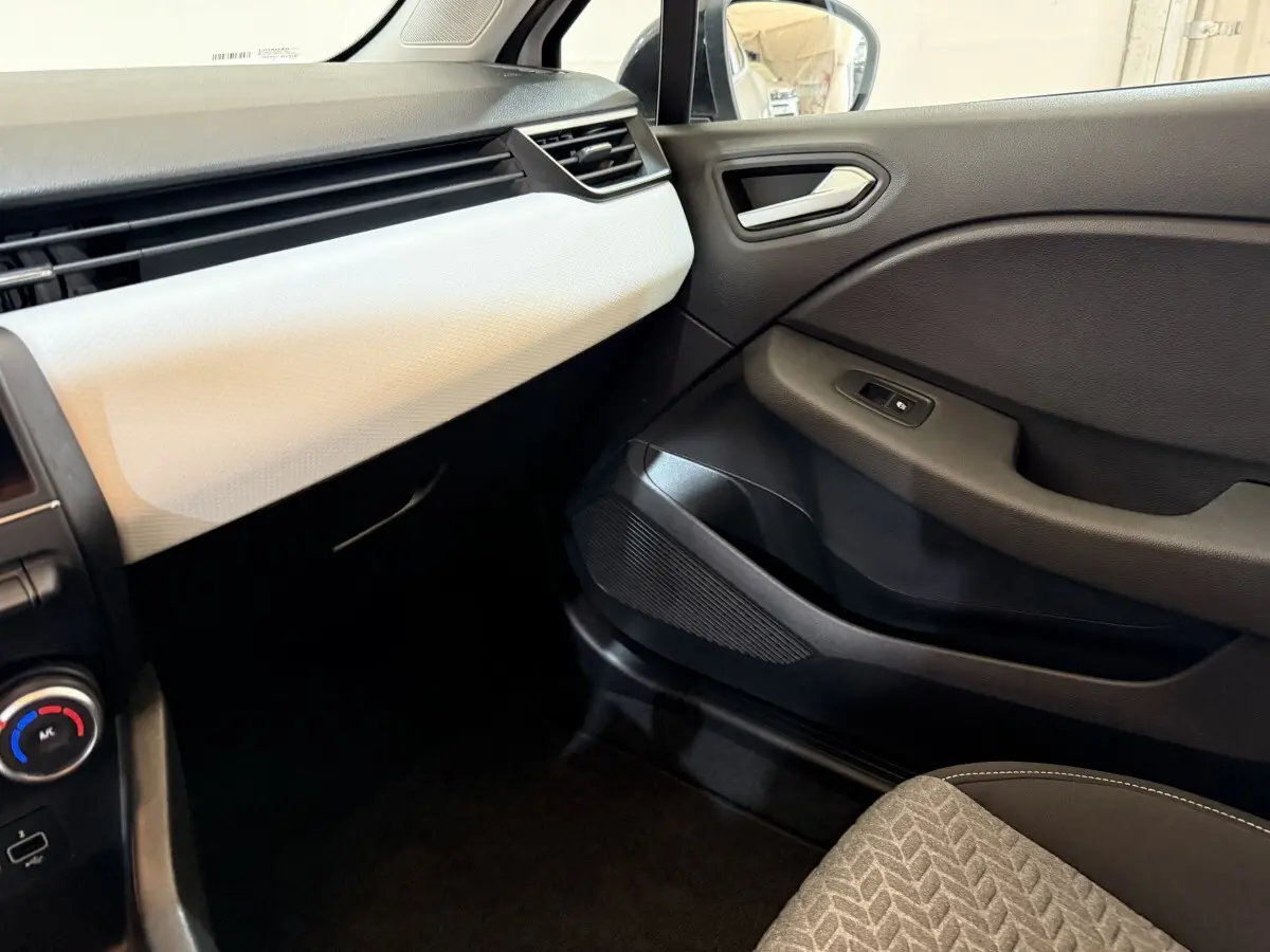 Vue intérieure côté passager de la Renault Clio Business TCe 100 GPL 2022, tableau de bord blanc et porte noire.