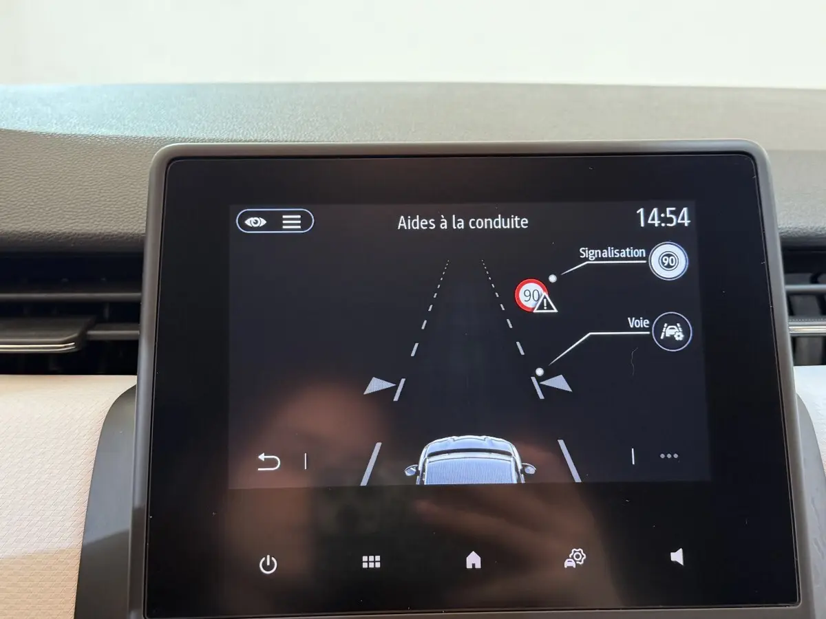 Écran tactile intérieur de la Renault Clio Business blanc, affichant les aides à la conduite et la signalisation.