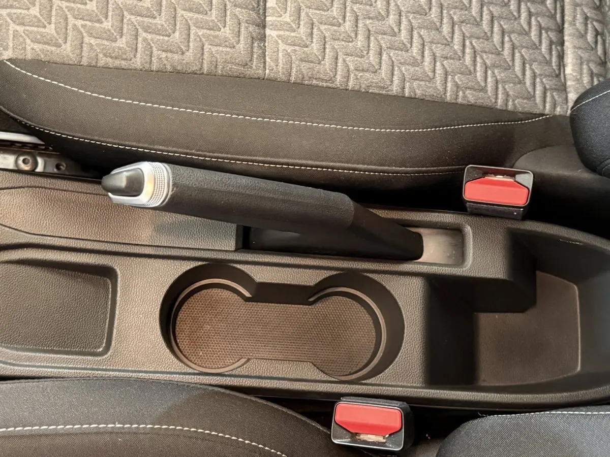 Vue rapprochée de la console centrale intérieure de la Renault Clio Business TCe 100 GPL 2022, avec frein à main manuel et porte-gobelets.