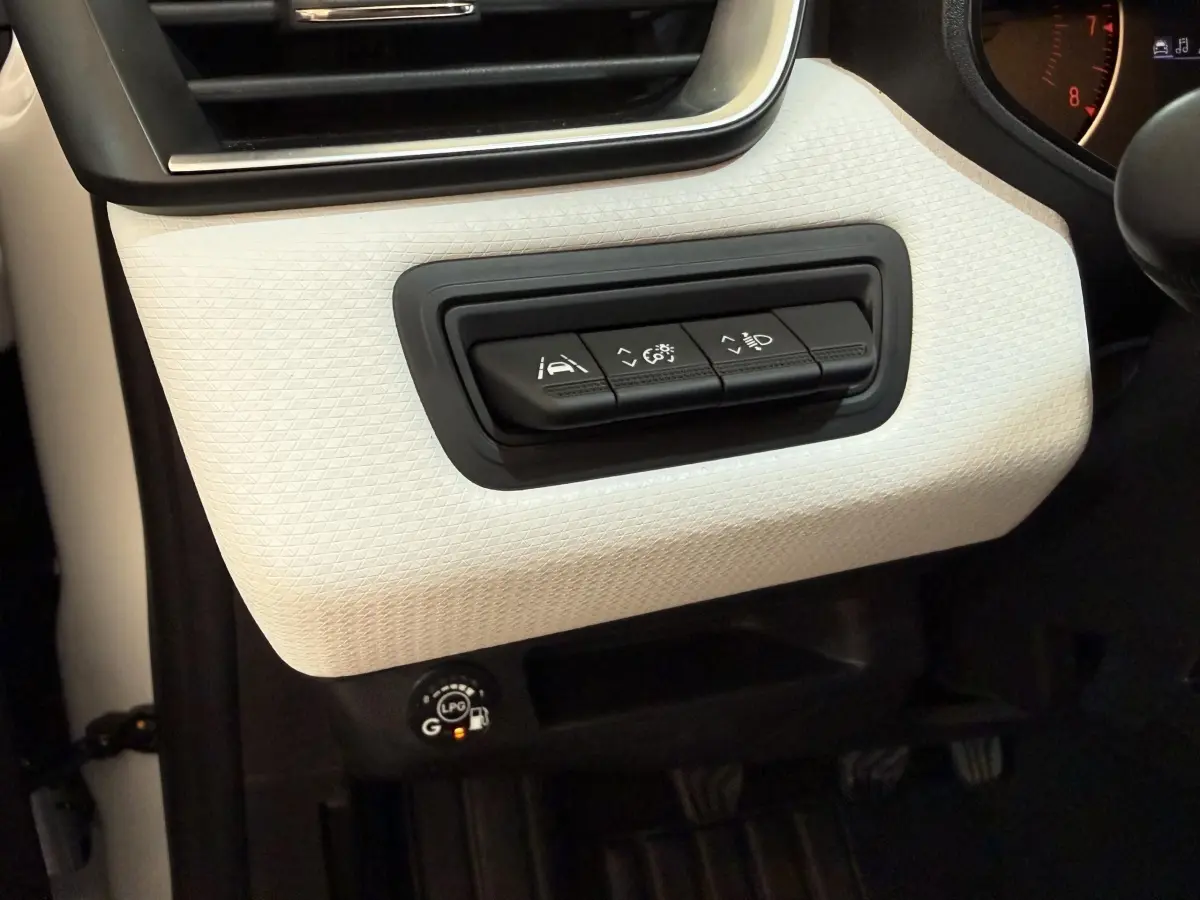 Détail intérieur côté gauche de la planche de bord blanche avec commandes d’aide à la conduite et bouton GPL allumé.