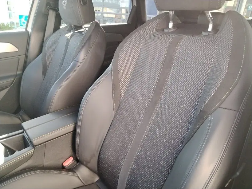 Gros plan sur les sièges avant en cuir et tissu noir de la Peugeot 308 SW Hybrid 145 GT, intérieur moderne et soigné.