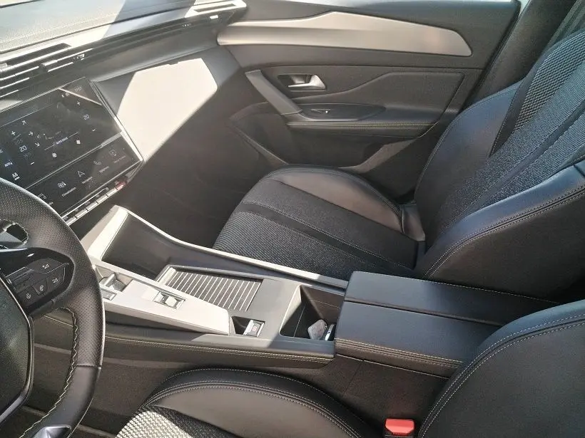 Intérieur de la Peugeot 308 SW Hybrid 145 GT, vue côté passager, sièges noirs et console centrale moderne.