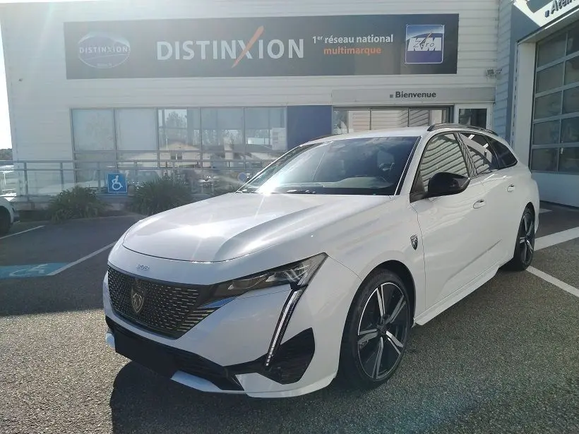 Peugeot 308 SW Hybrid 145 GT blanc Okenite vue 3/4 avant droit avec calandre noire et jantes alliage.