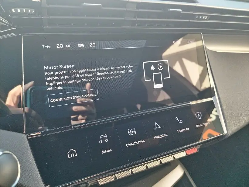 Écran tactile central de la Peugeot 308 SW Hybrid 145 GT 2025, affichant les options Mirror Screen et climatisation.