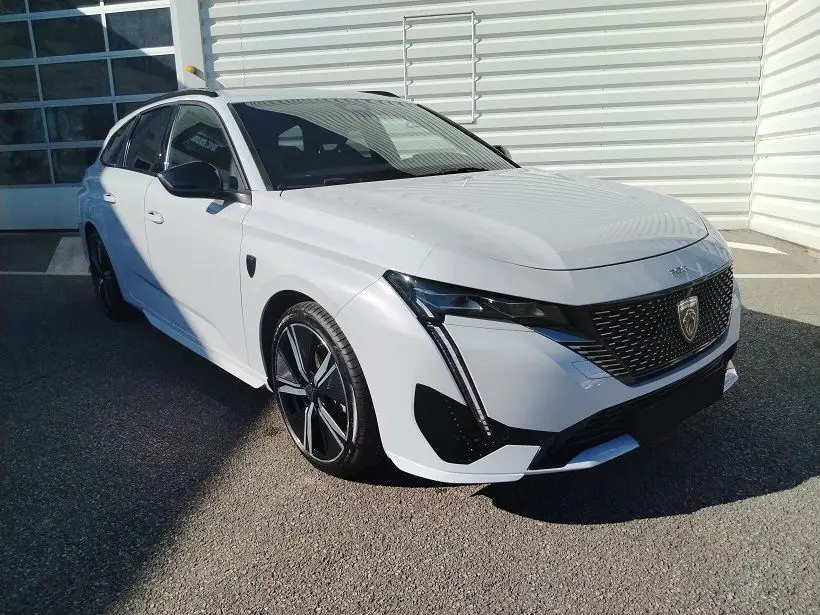 Peugeot 308 SW Hybrid 145 GT blanc Okenite vue 3/4 avant droit, avec calandre noire et jantes alliage noires.