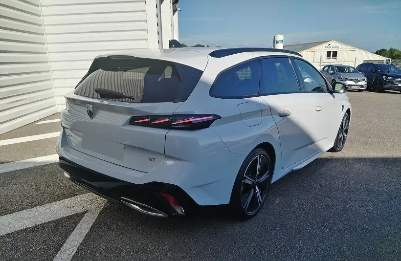 Peugeot 308 SW Hybrid 145 GT blanc Okenite vue 3/4 arrière droit, feux arrière LED et jantes alliage noires.