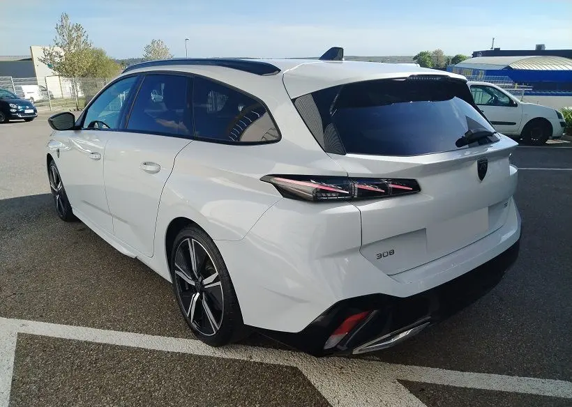 Peugeot 308 SW Hybrid 145 GT blanc Okenite vue 3/4 arrière droit, feux arrière LED et jantes alliage noires.