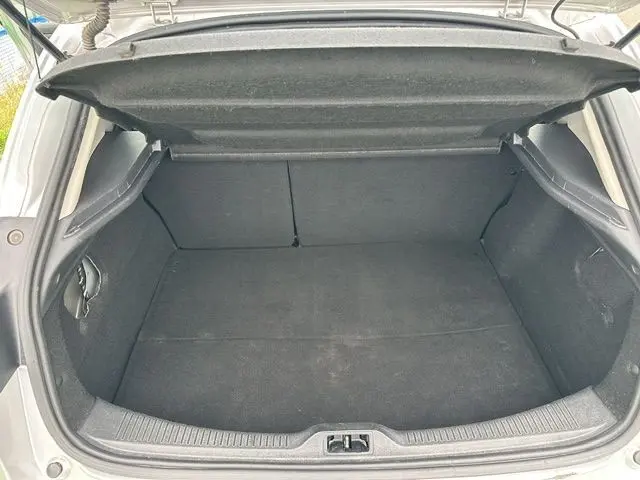 Coffre ouvert vu de l'arrière d'une Renault Mégane 3 gris, montrant un espace de chargement propre et spacieux.