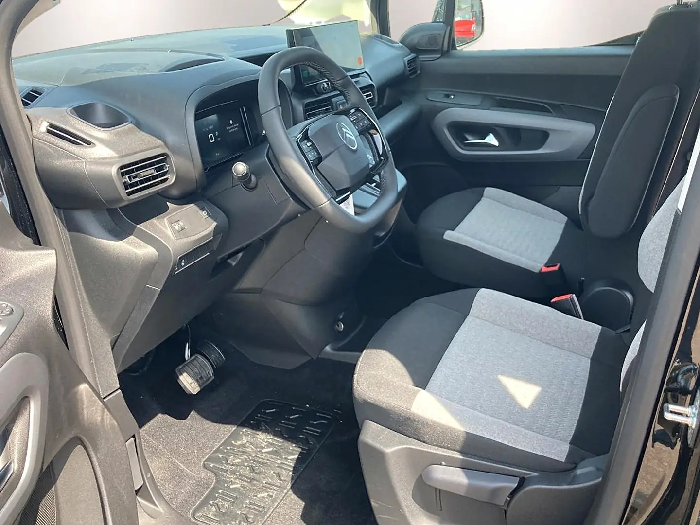 Vue intérieure côté conducteur du Citroën Berlingo noir 2026, montrant le tableau de bord et les sièges bicolores gris et noir.