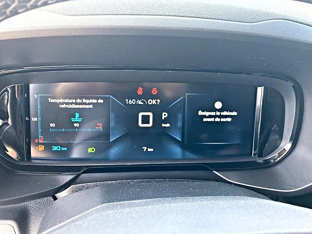 Vue rapprochée du tableau de bord numérique du Citroën Berlingo noir, affichant la température moteur et la vitesse.