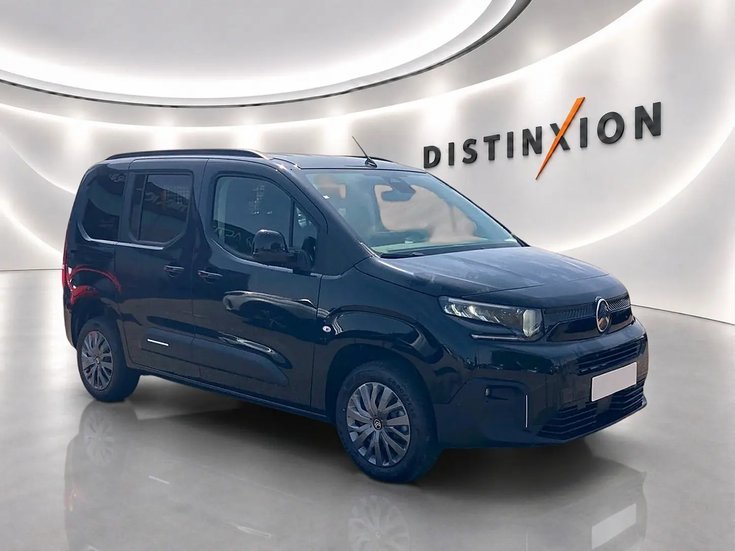 Vue 3/4 avant droite d'un Citroën Berlingo noir 2026 avec barres de toit et jantes alu en showroom.