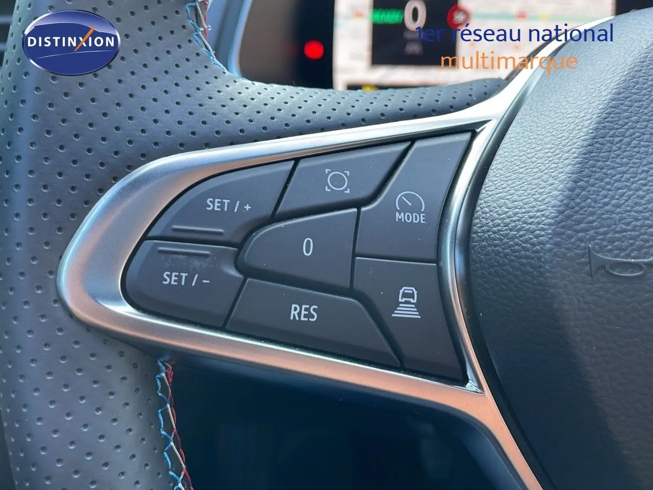 Gros plan sur les commandes de régulateur de vitesse au volant cuir perforé du Renault Captur E-Tech hybride 2025.