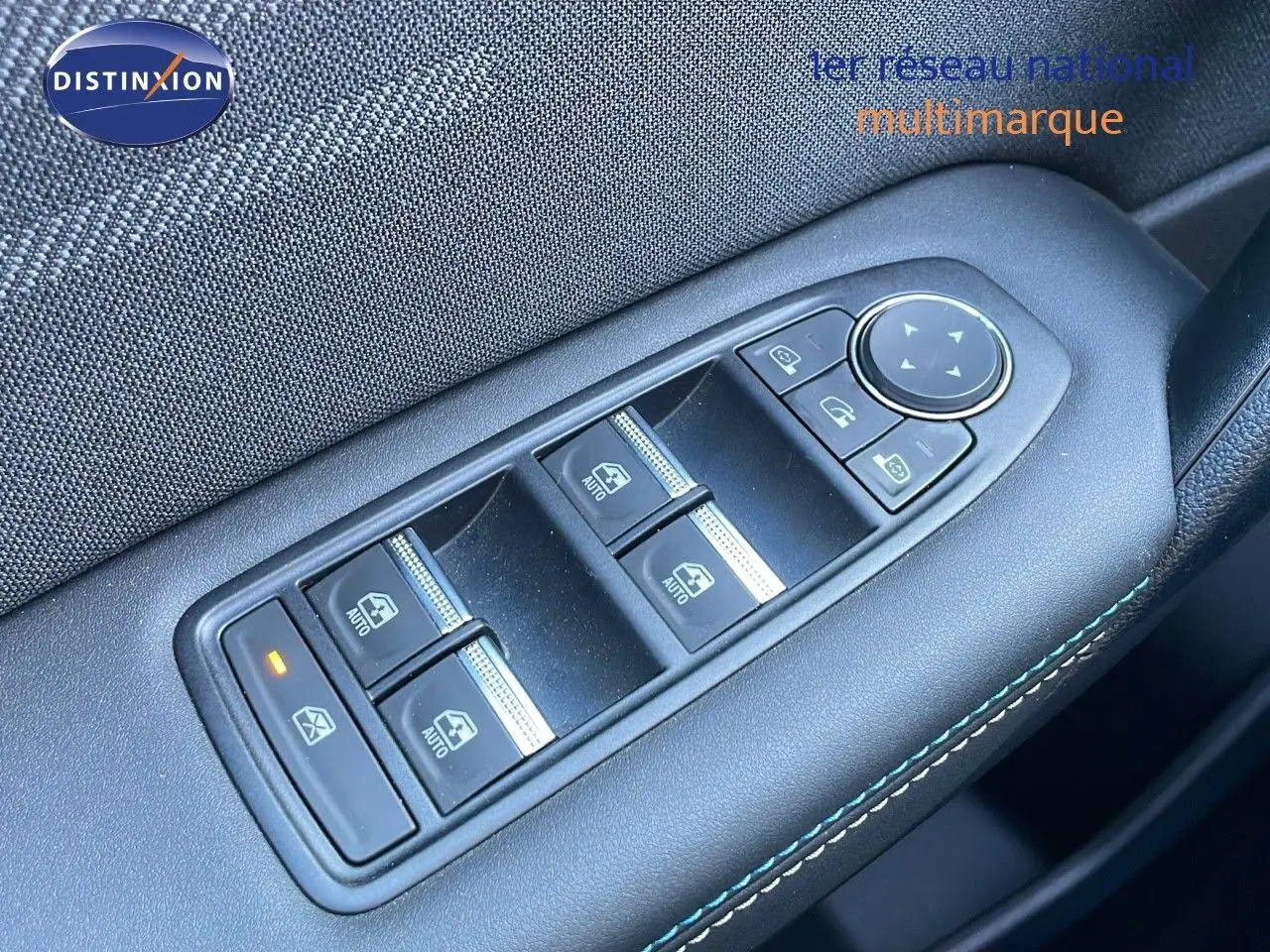 Gros plan sur les commandes des vitres électriques côté conducteur d'un Renault Captur bleu Iron Metal toit noir 2025.