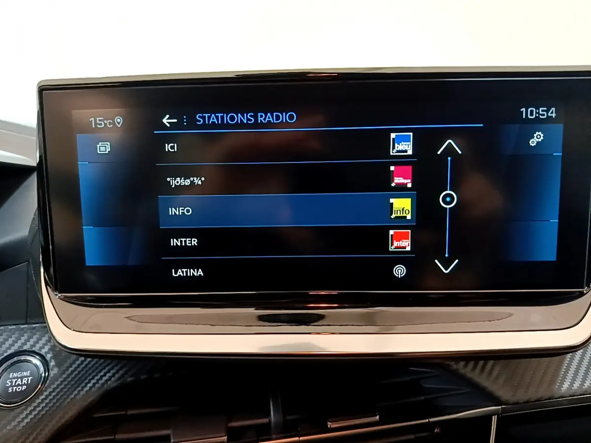 Écran tactile central affichant les stations radio dans l'habitacle d'une Peugeot 208 gris foncé de 2022.