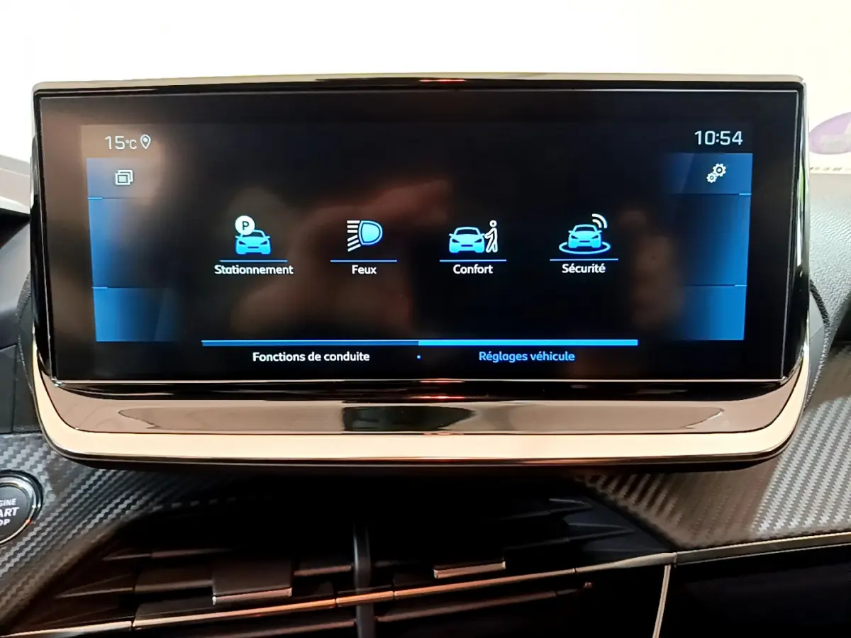 Écran tactile central affichant les réglages véhicule dans l'habitacle d'une Peugeot 208 gris foncé, vue de face rapprochée.