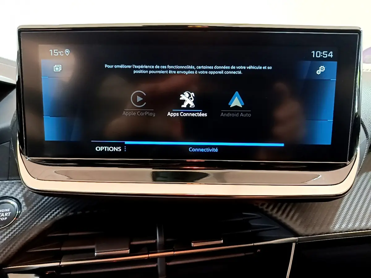 Écran tactile central affichant Apple CarPlay et Android Auto sur tableau de bord carbone d'une Peugeot 208 2022.