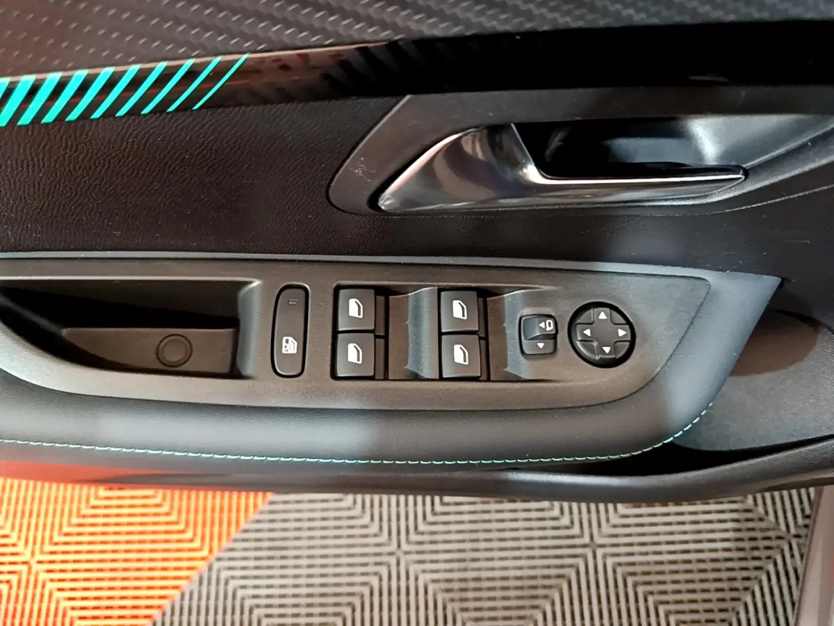 Commande des vitres et rétroviseurs sur la porte côté conducteur d'une Peugeot 208 gris foncé avec surpiqûres bleues.