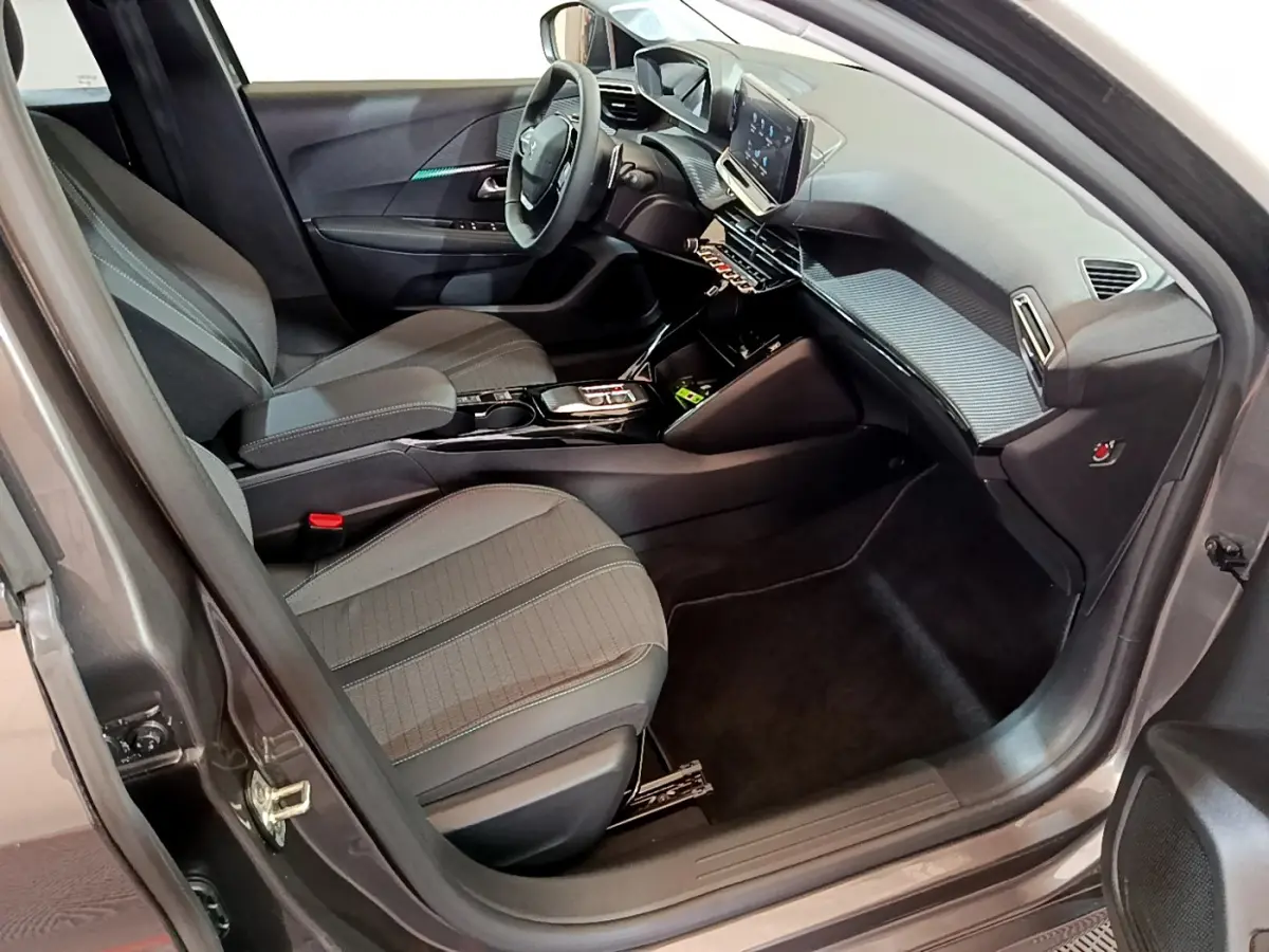 Intérieur côté conducteur de la Peugeot 208 gris foncé 2022, avec tableau de bord moderne et écran tactile central.