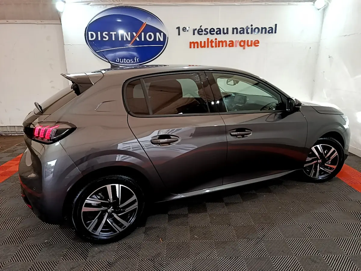 Peugeot 208 gris foncé vue de profil côté gauche, avec jantes alliage et feux arrière LED allumés.