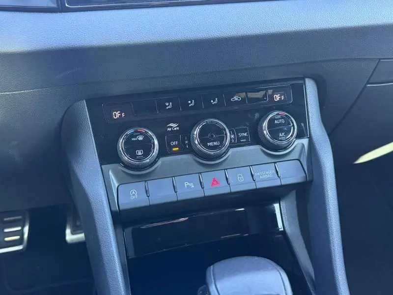 Vue rapprochée de la console centrale grise du Skoda Karoq 2025 avec commandes de climatisation et boutons fonctionnels.